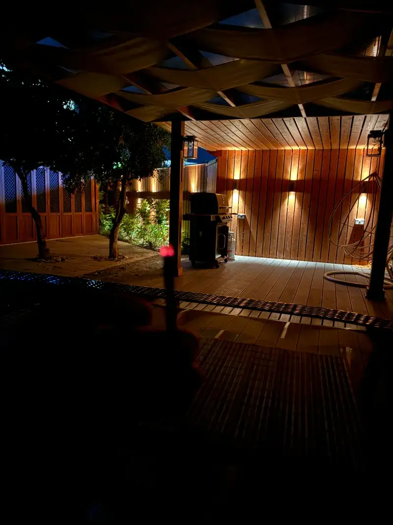 BBQ terrace with wooden pergola and warm evening lighting