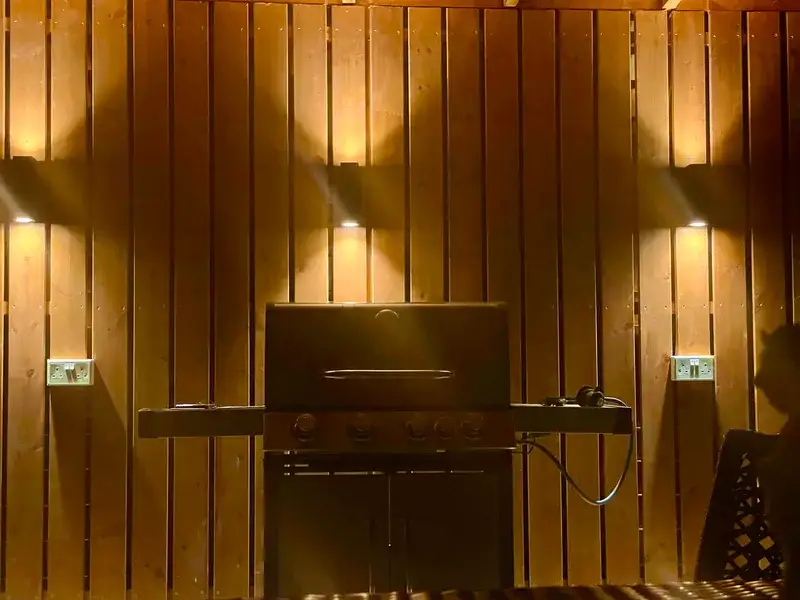 BBQ grill with atmospheric wall lighting on cedar panels